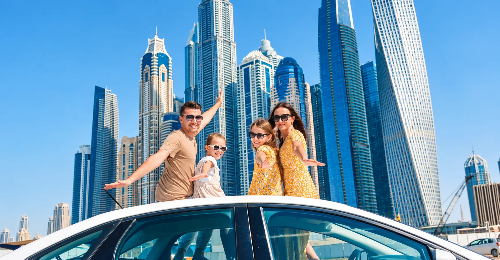 Family posing through a car sunroof with the Dubai Marina skyline behind them