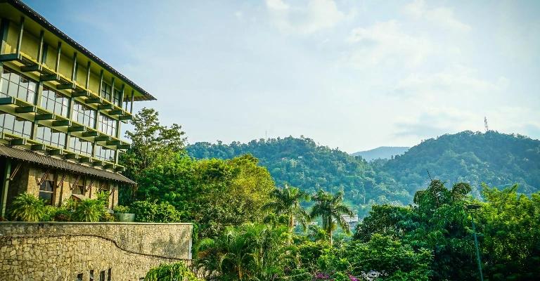 A hillside building overlooking a green valley and mountains.