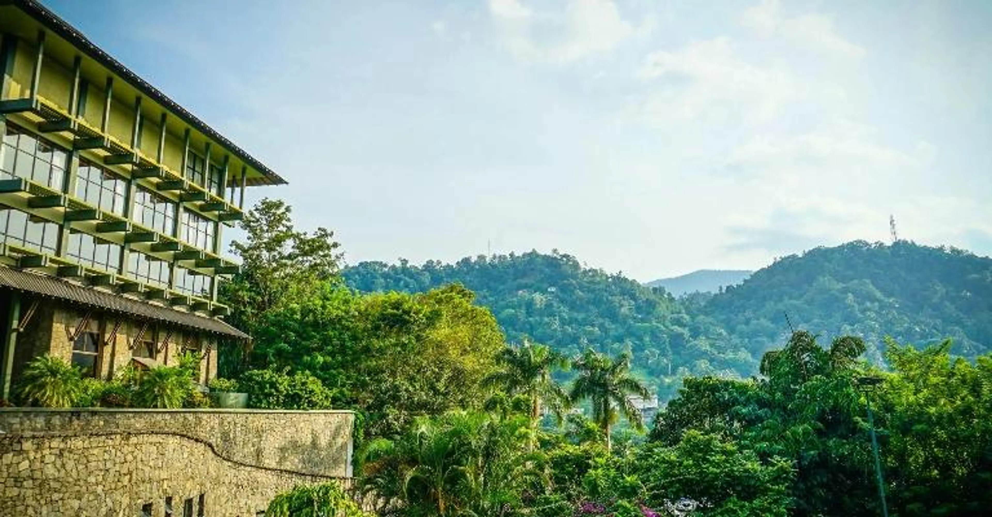 A hillside building overlooking a green valley and mountains.