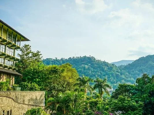 A hillside building overlooking a green valley and mountains.