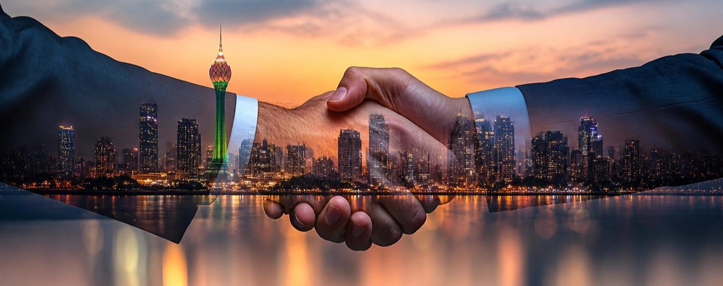 Two hands shaking with the Colombo skyline at dusk overlaid in the background.