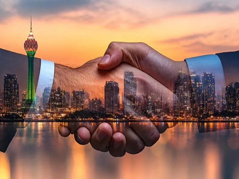 Two hands shaking with the Colombo skyline at dusk overlaid in the background.