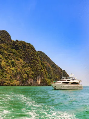 Private luxury yacht cruising the emerald waters and limestone cliffs of Phang Nga Bay, Thailand