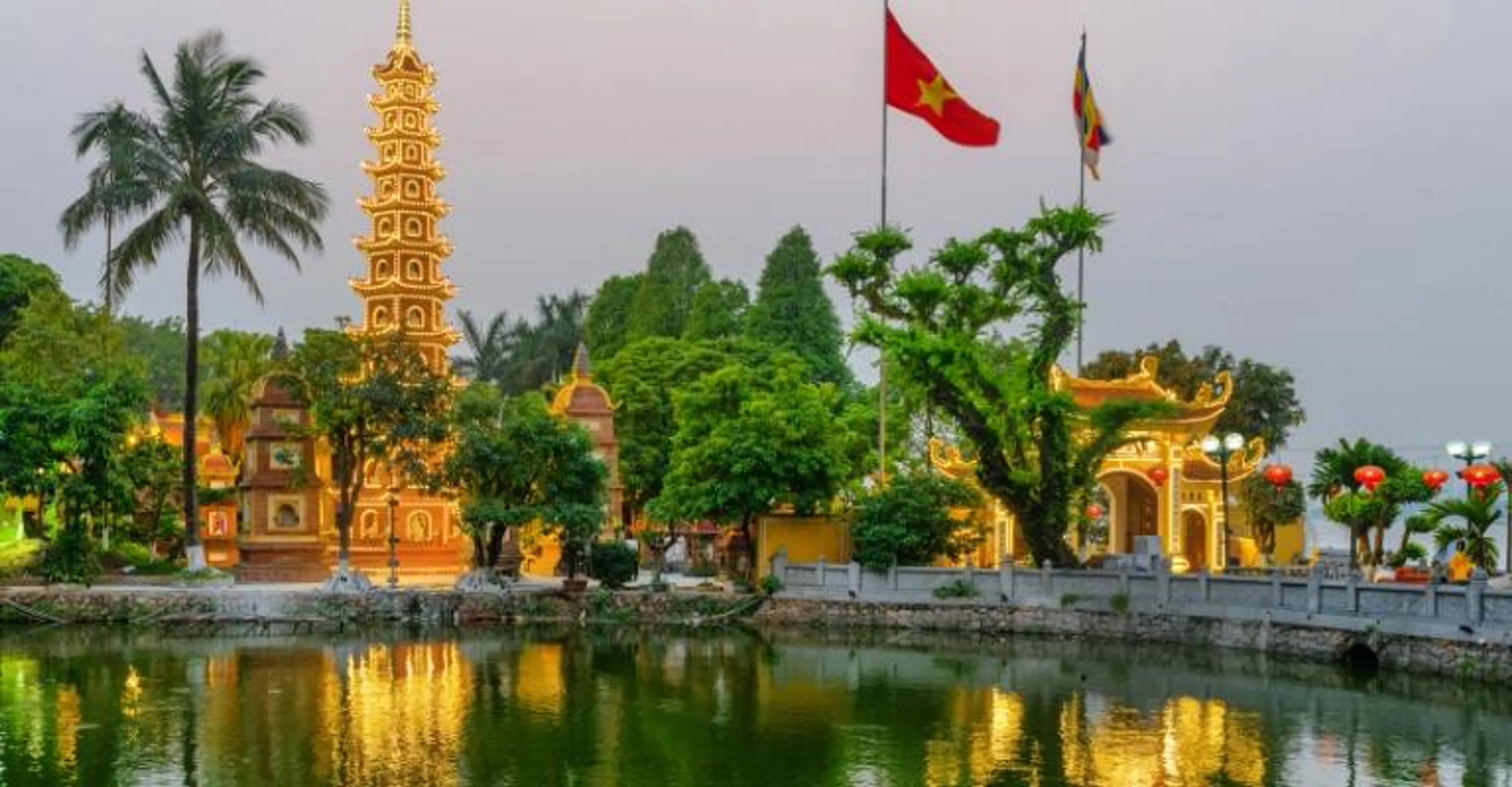 Tran Quoc Pagoda in Hanoi lit at dusk, reflected in West Lake