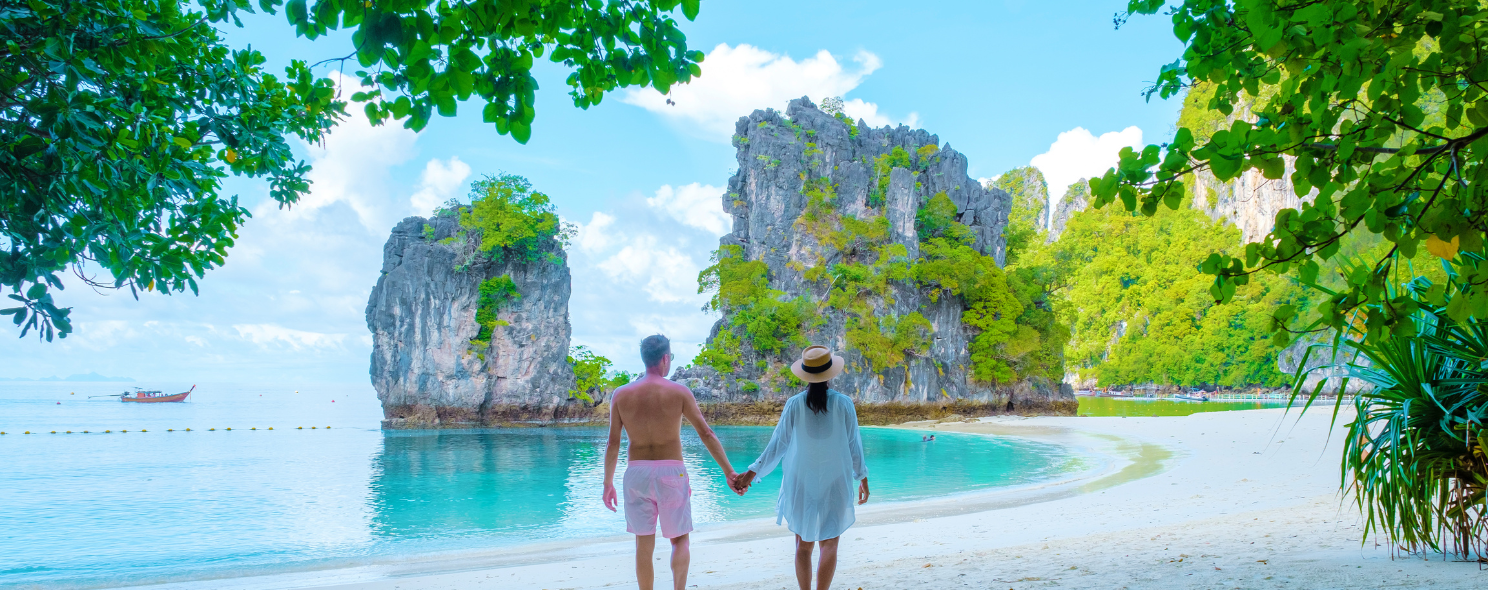 Couple holding hands on a white sand beach facing limestone rocks at Koh Hong, Krabi, Thailand