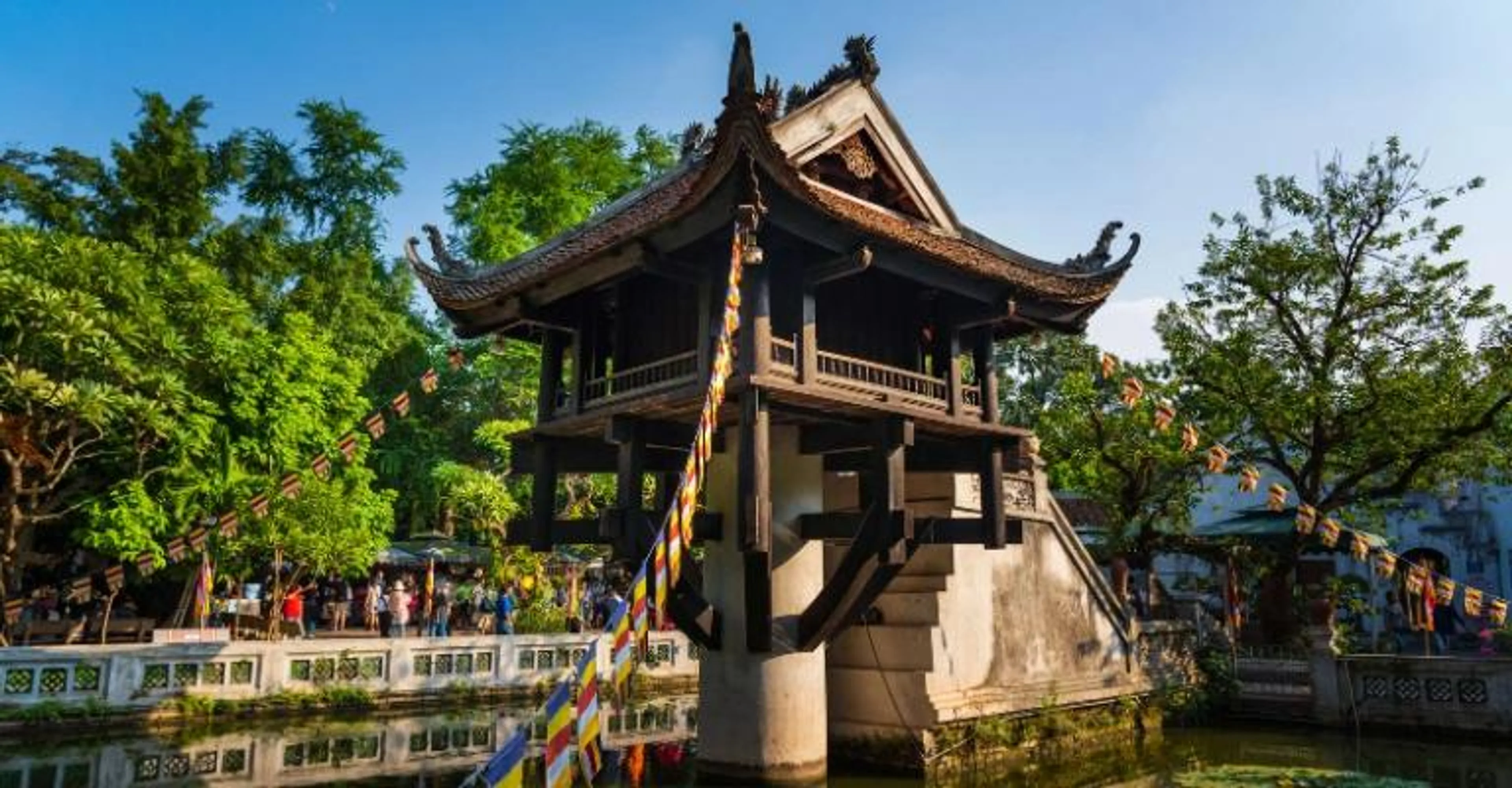 The One Pillar Pagoda on stilts above a lotus pond in Hanoi, decorated with colorful prayer flags