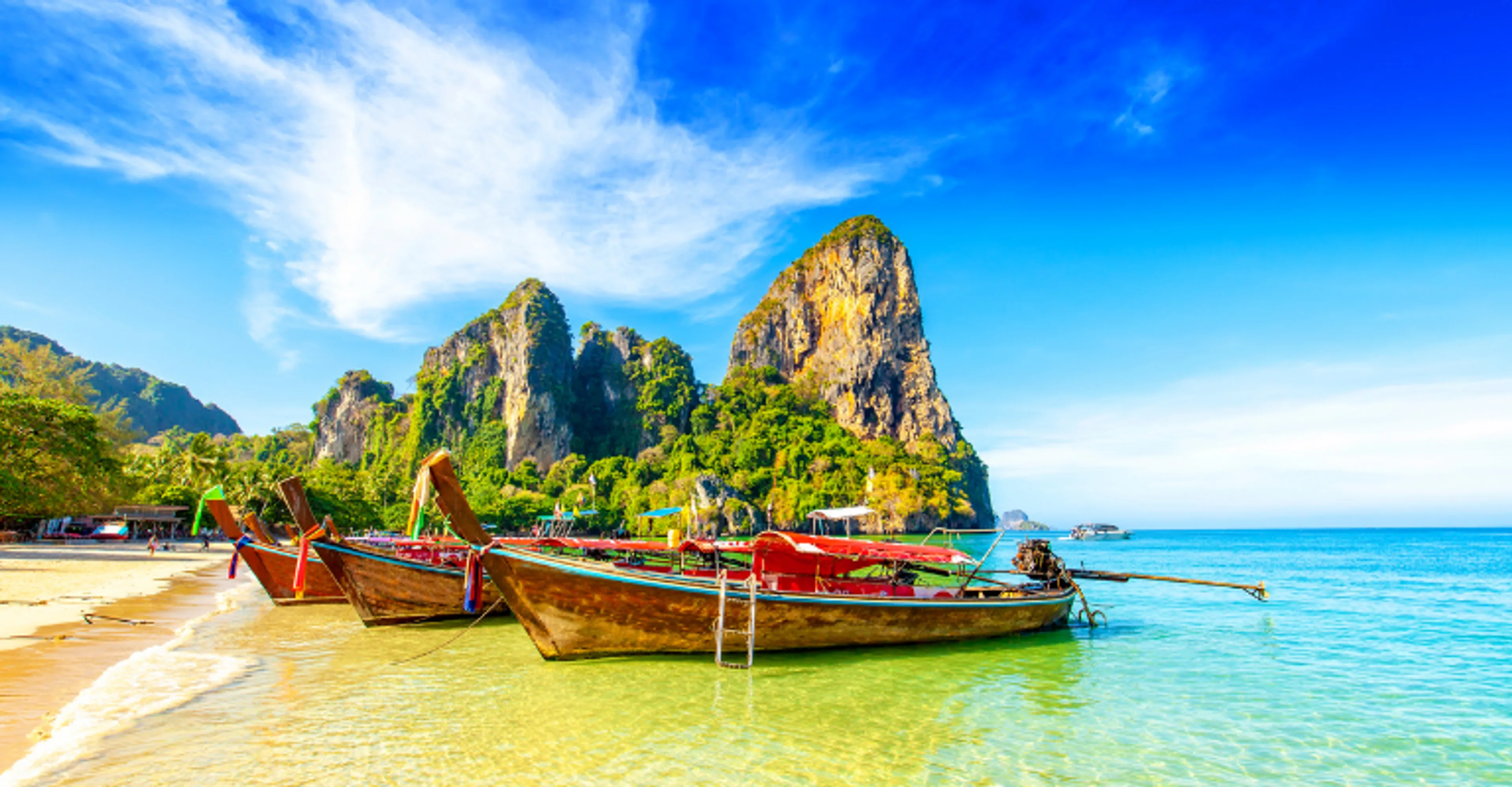 Longtail boats on Railay Beach with limestone cliffs in Krabi, Thailand