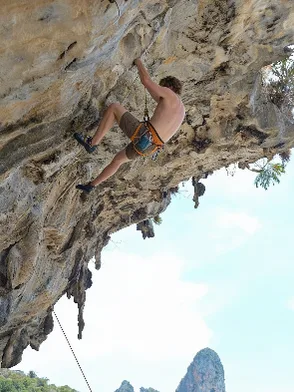 Rock climber scaling limestone cliffs above the sea on Cát Bà Island Vietnam
