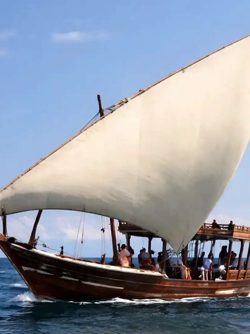Traditional dhow boat sailing at sunset along the Kenyan coast