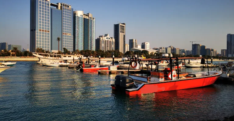 Tour boats docked at a marina with the Abu Dhabi skyline