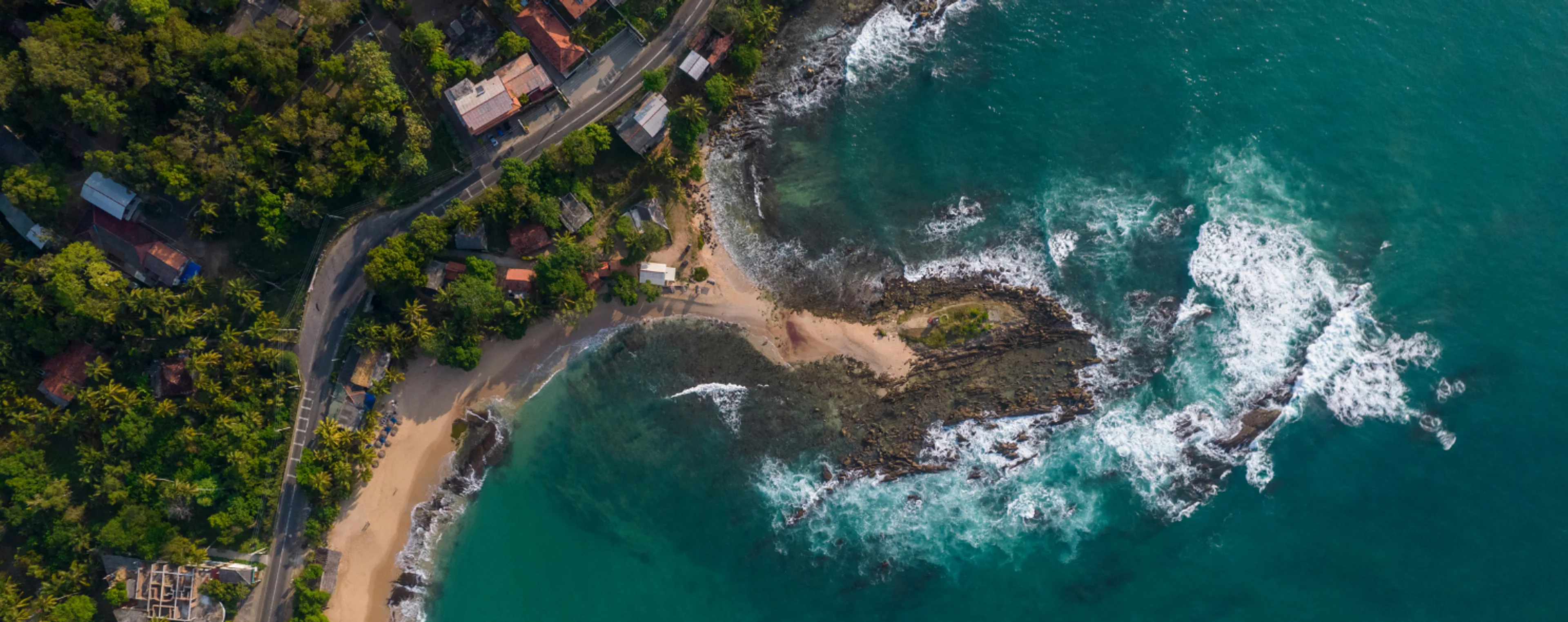 Aerial view of a tropical beach and rocky coastline.