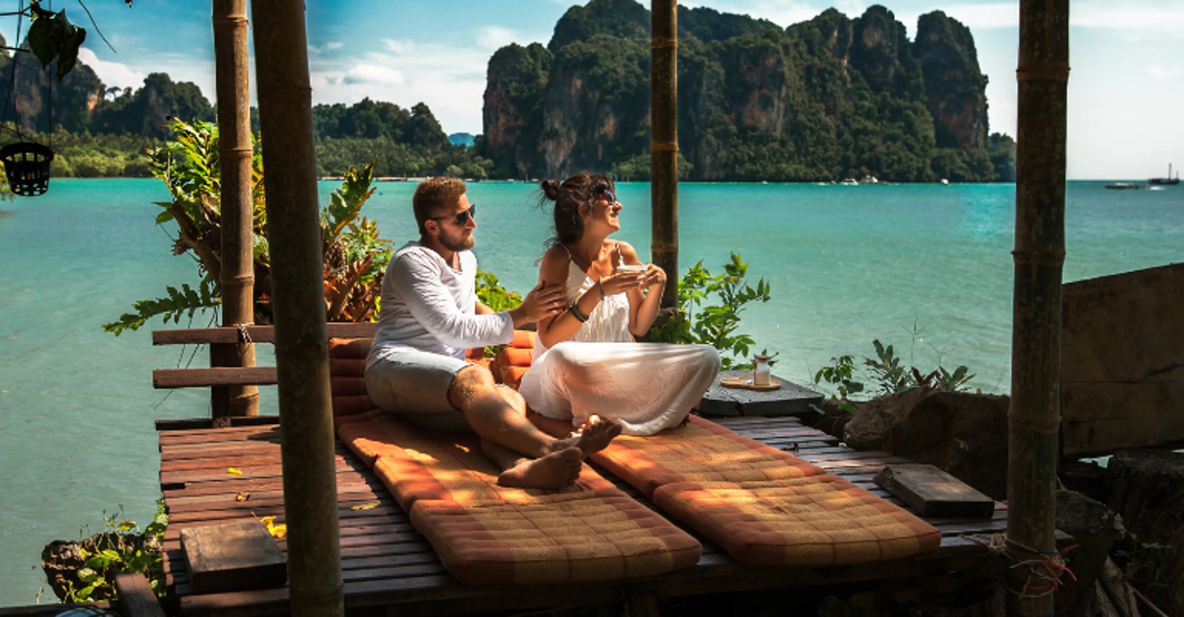 Couple relaxing on a wooden deck with views of Krabi’s limestone cliffs, Thailand