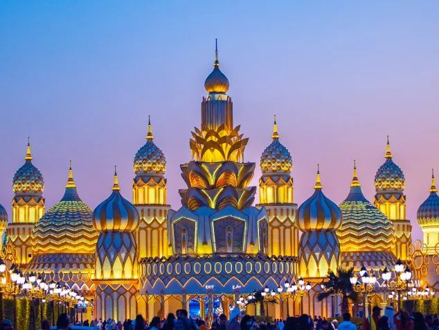 Golden onion-domed pavilion at Dubai Global Village under a glowing sky.