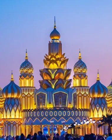 Golden onion-domed pavilion at Dubai Global Village under a glowing sky.