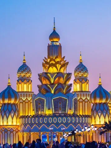 Golden onion-domed pavilion at Dubai Global Village under a glowing sky.