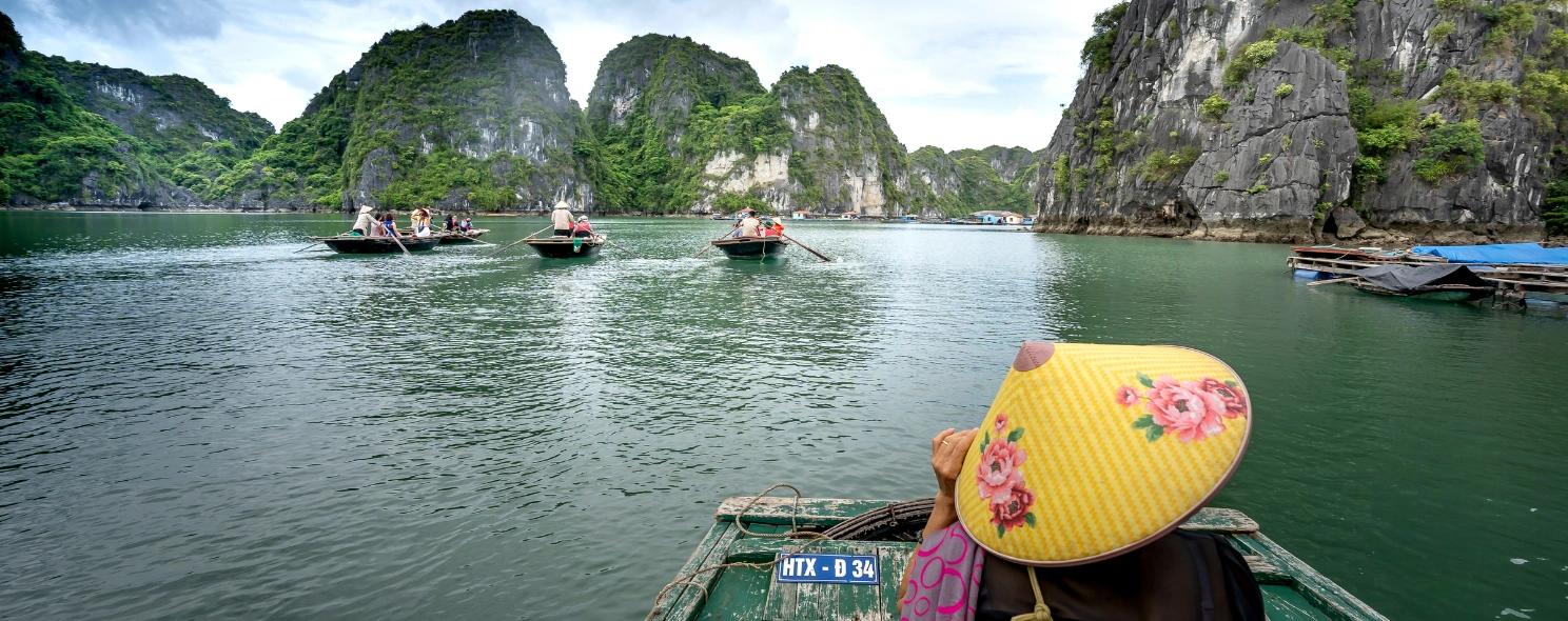 Rowboats crossing Halong Bay past limestone karsts
