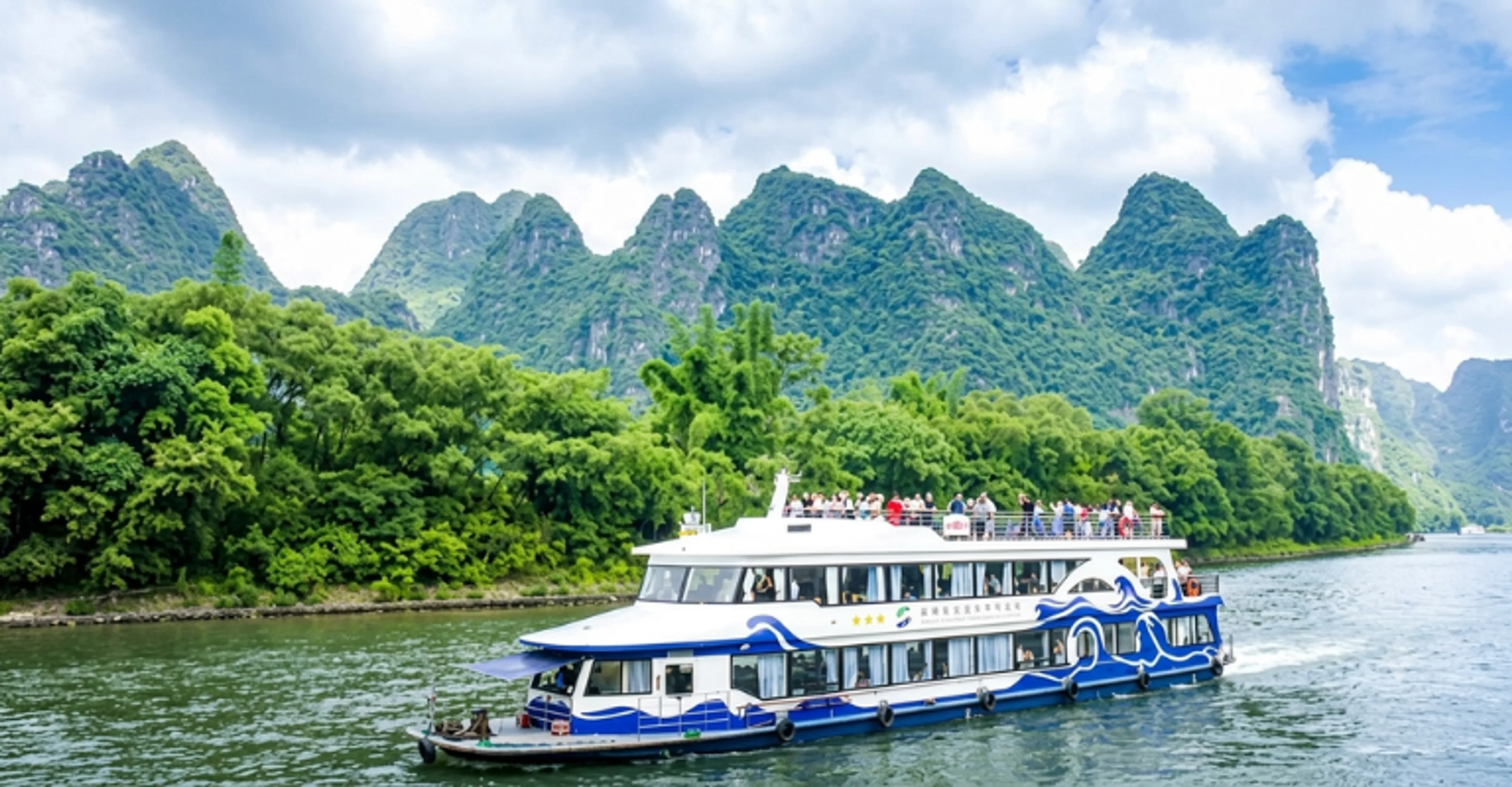 Tourist cruise boat sailing past karst mountain peaks on the Li River near Guilin