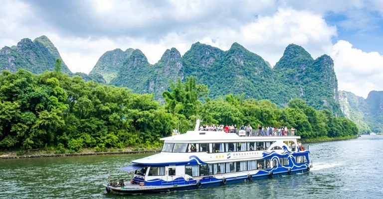 Tourist cruise boat sailing past karst mountain peaks on the Li River near Guilin
