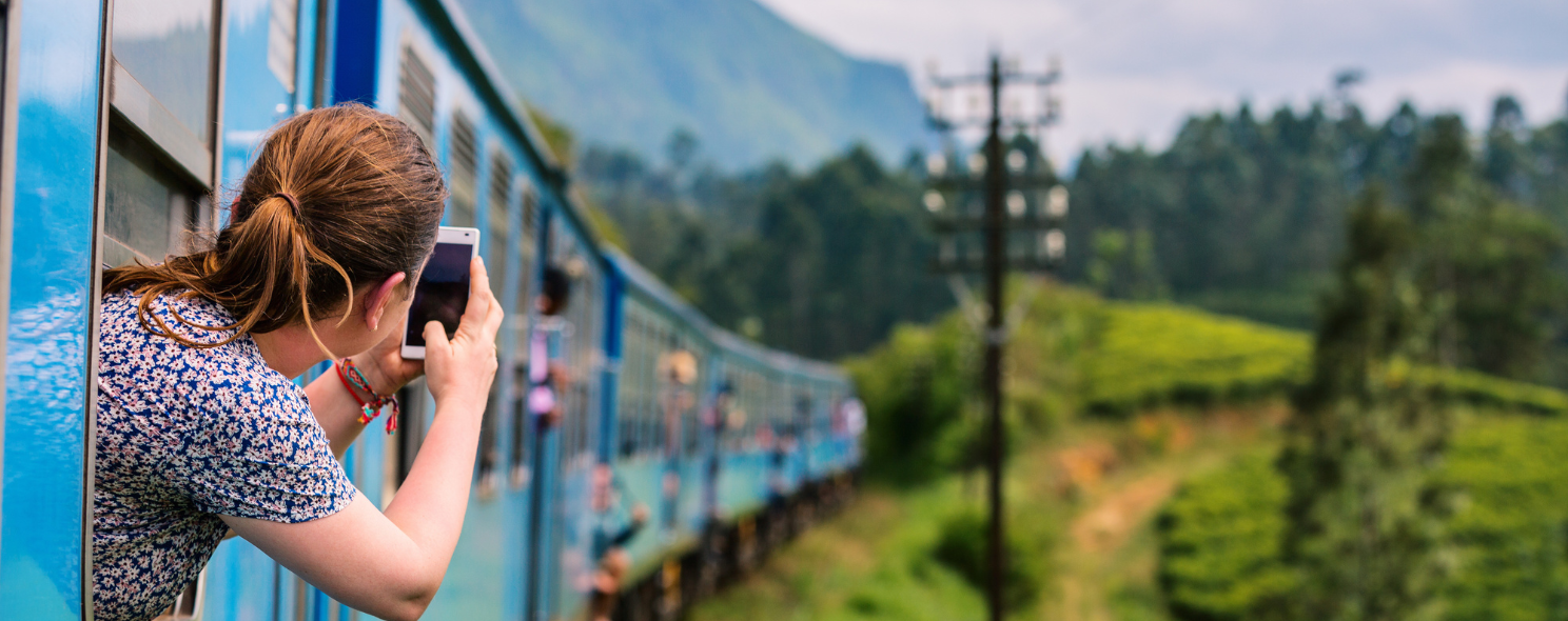 A traveler photographing tea plantations from a train window in Sri Lanka's hill country