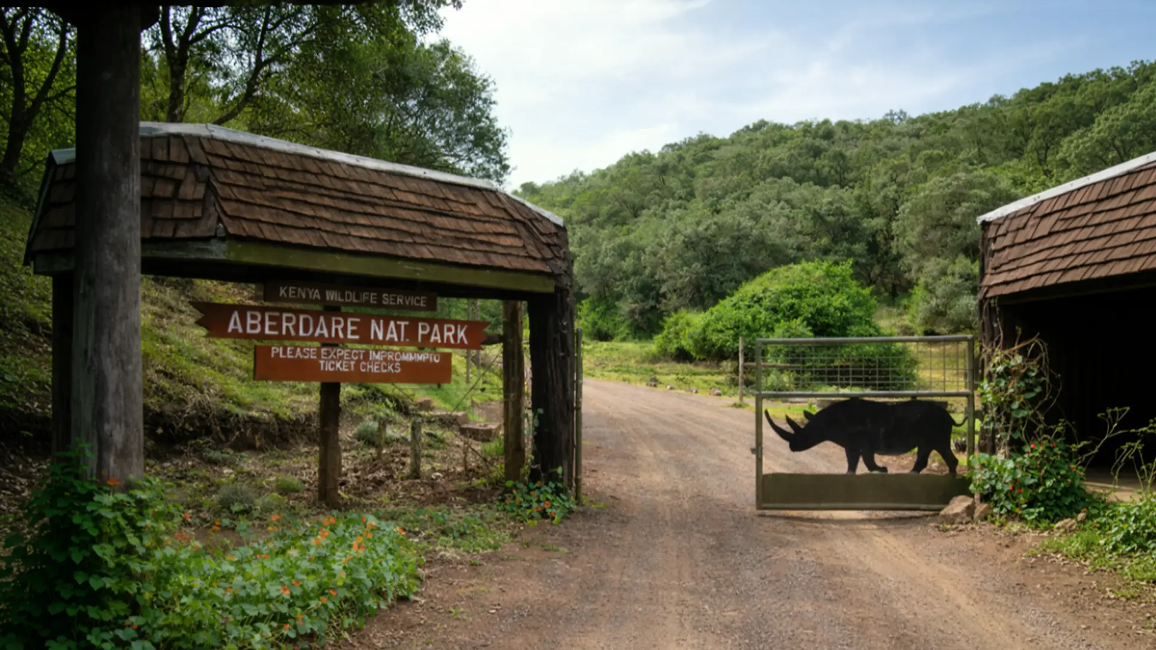 A dirt road leading through the rhino-gate entrance of Aberdare National Park in Kenya