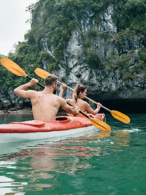 Kayakers paddling through emerald waters and limestone karsts of Lan Hạ Bay Vietnam