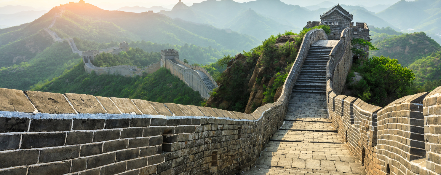 Sunrise view along the Great Wall of China winding through forested mountains