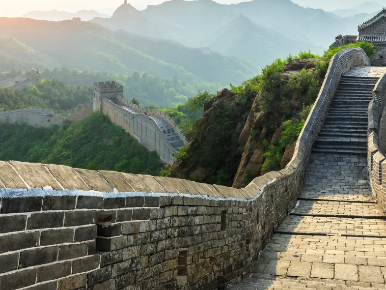 Sunrise view along the Great Wall of China winding through forested mountains