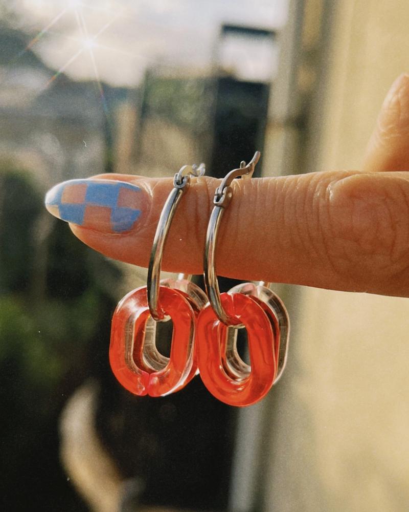pendientes de acero con dijes de plastico en tonos de rojo