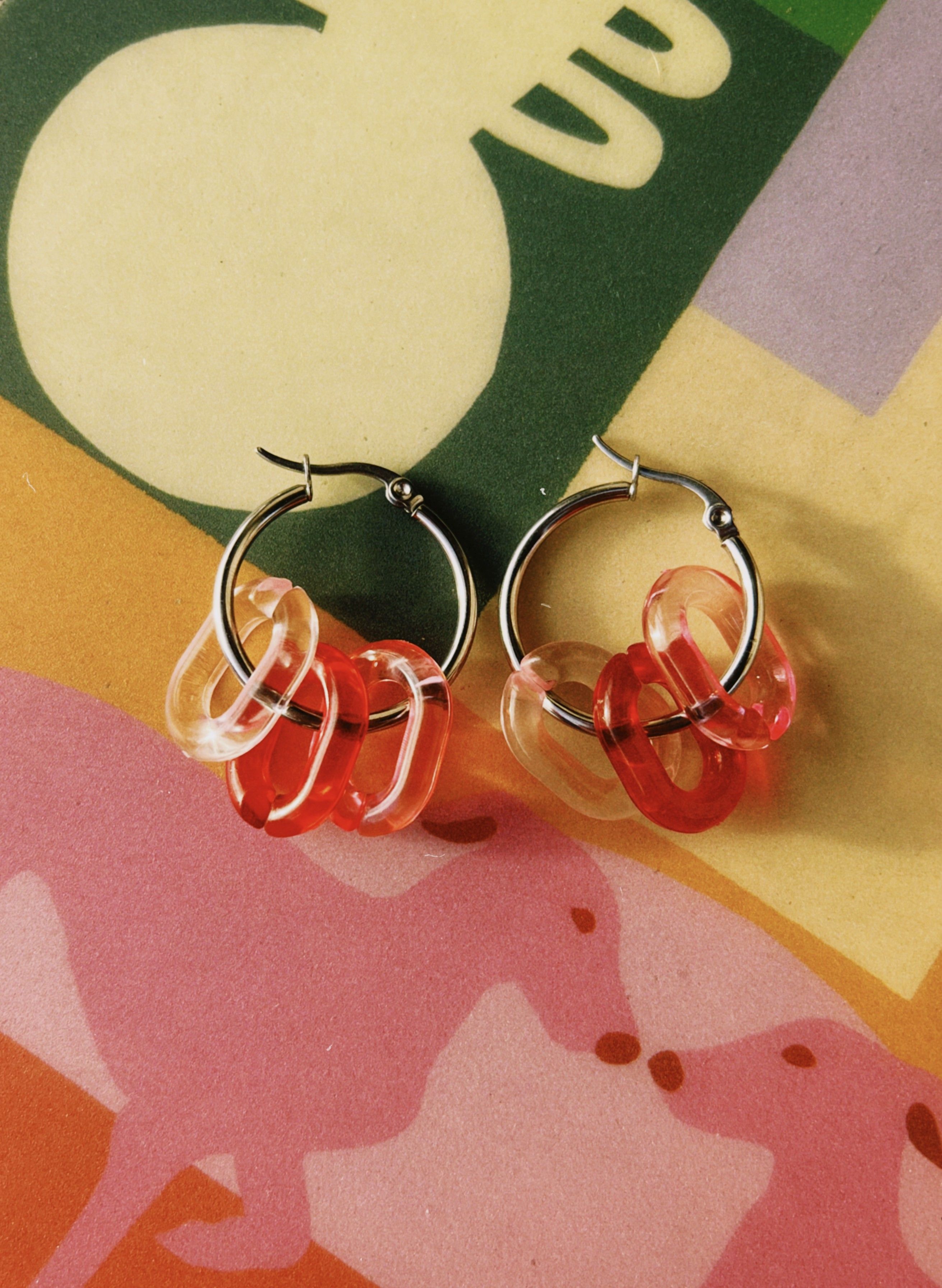 pendientes de acero quirúrgico con dijes en tonos rojos y rosas