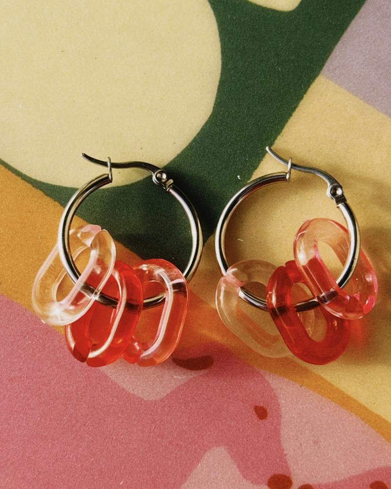 pendientes de acero quirúrgico con dijes en tonos rojos y rosas