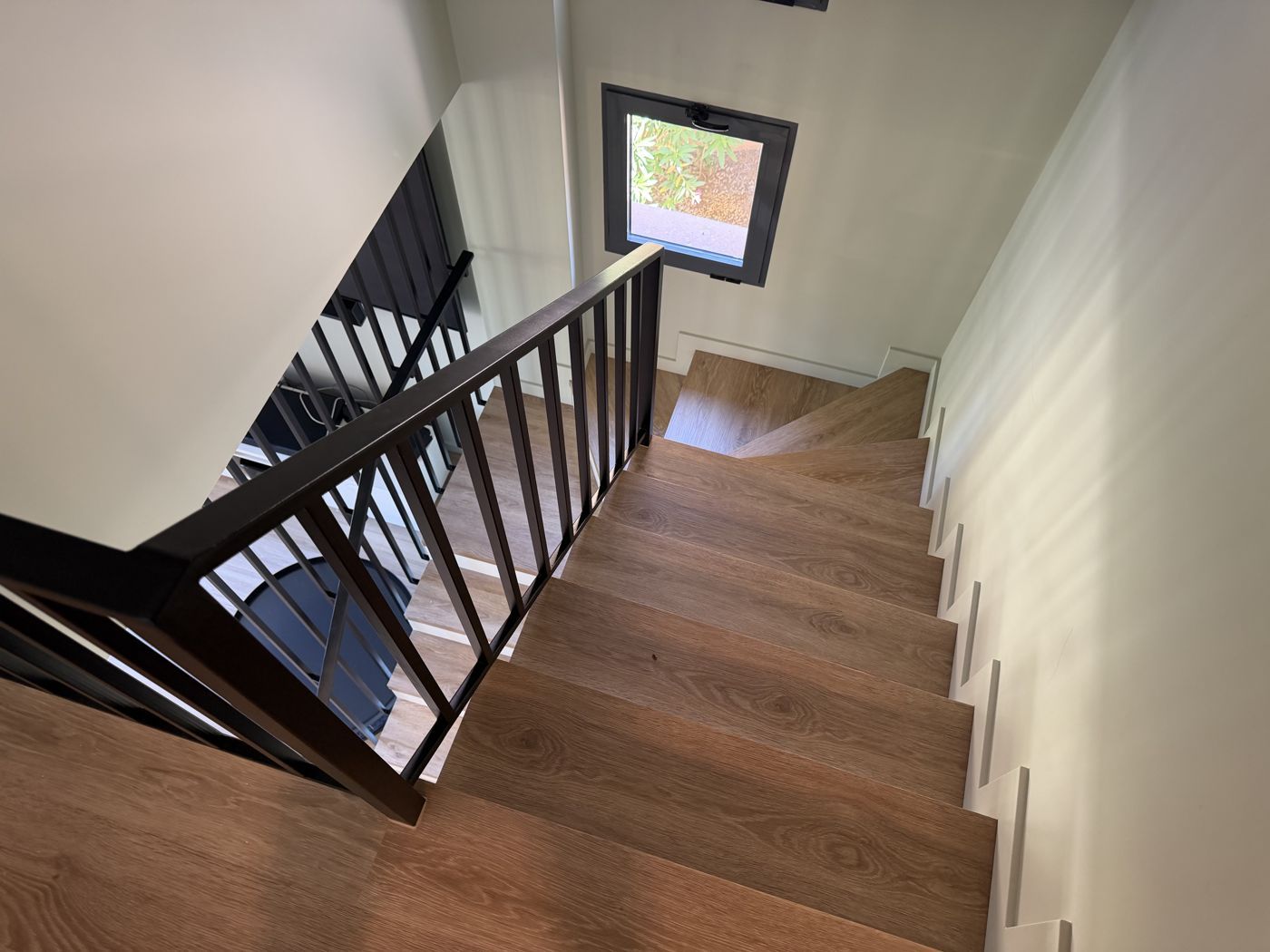 Escalera reformada con peldaños de madera y barandilla metálica negra