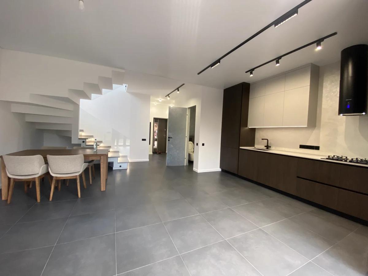 Salón-cocina abierto tras una reforma integral de vivienda en Valencia, con escalera y suelo porcelánico