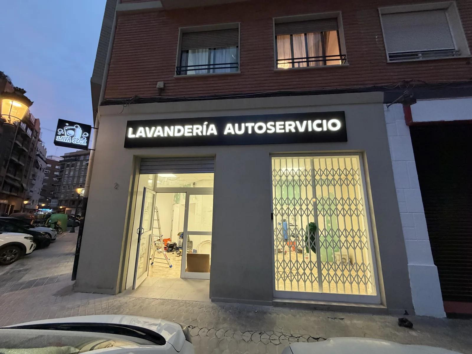 Fachada terminada de la lavandería autoservicio en Valencia, de noche, con rótulo iluminado