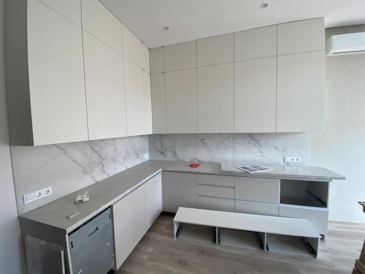 Cocina blanca a medida con encimera y frente imitación mármol en una reforma en Valencia