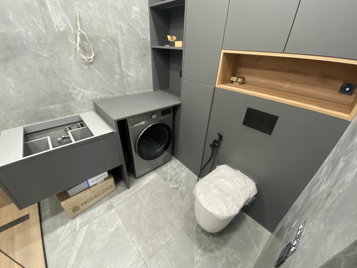 Baño con inodoro suspendido, mueble a medida y hueco para lavadora