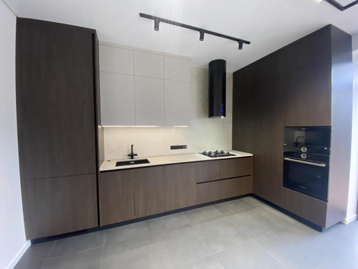 Cocina reformada en Valencia con muebles en madera oscura, campana negra e iluminación en carril