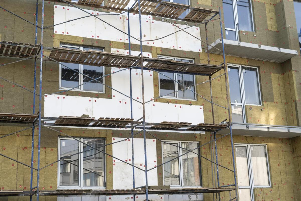 Instalación de SATE en la fachada de un edificio de viviendas con andamio: paneles de lana mineral fijados a la pared