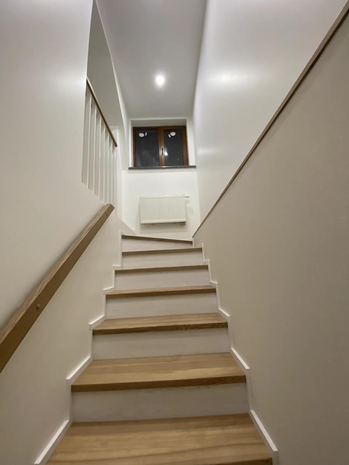 Escalera interior revestida de madera con pasamanos empotrado tras la reforma
