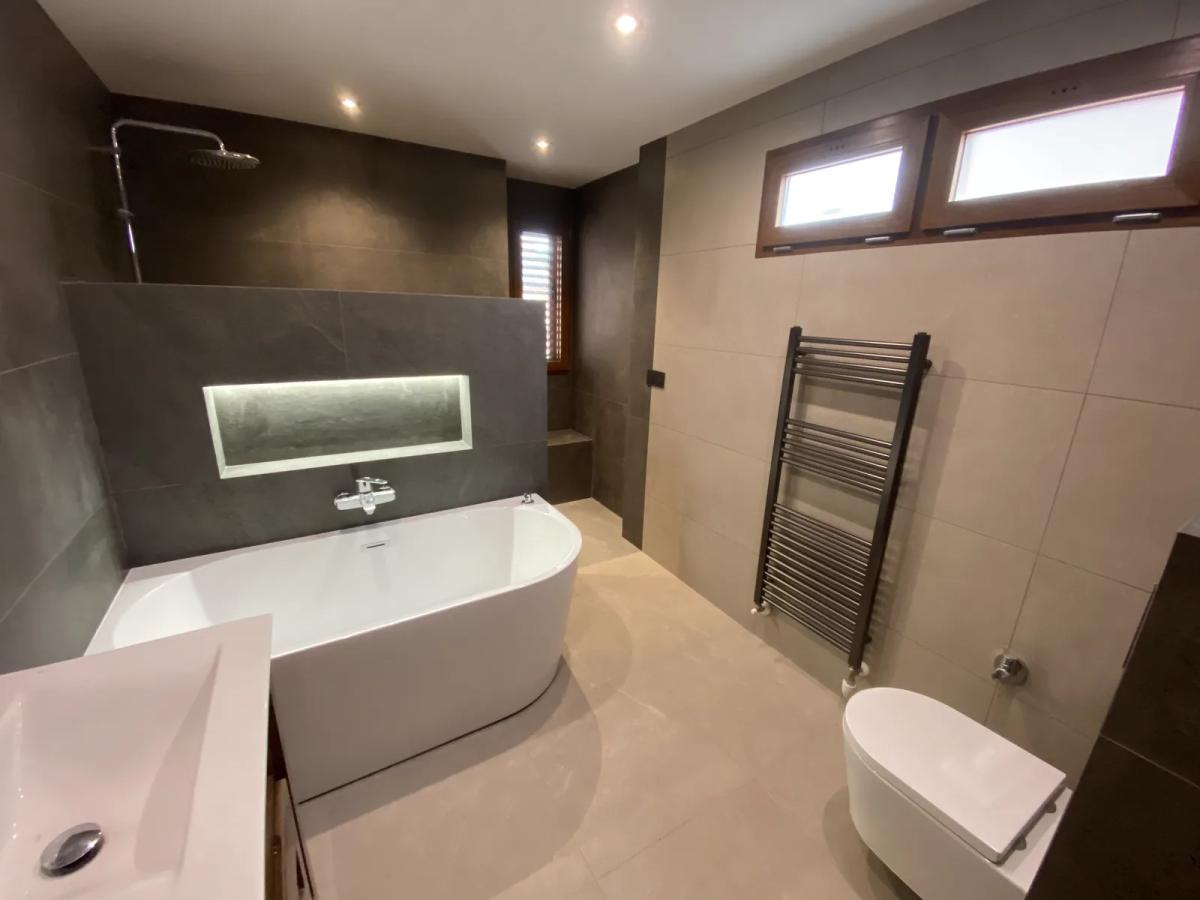 Baño reformado en Valencia con bañera exenta, porcelánico gris, hornacina con LED y toallero