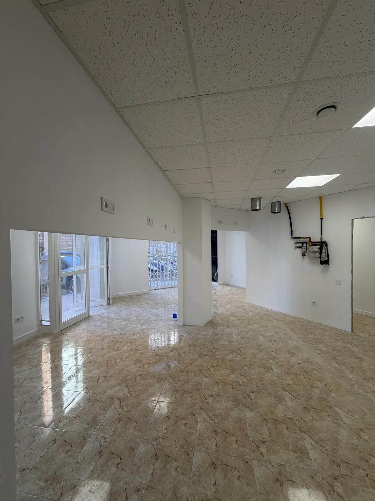 Interior terminado de la lavandería: techo registrable, suelo de mármol y escaparate a la calle