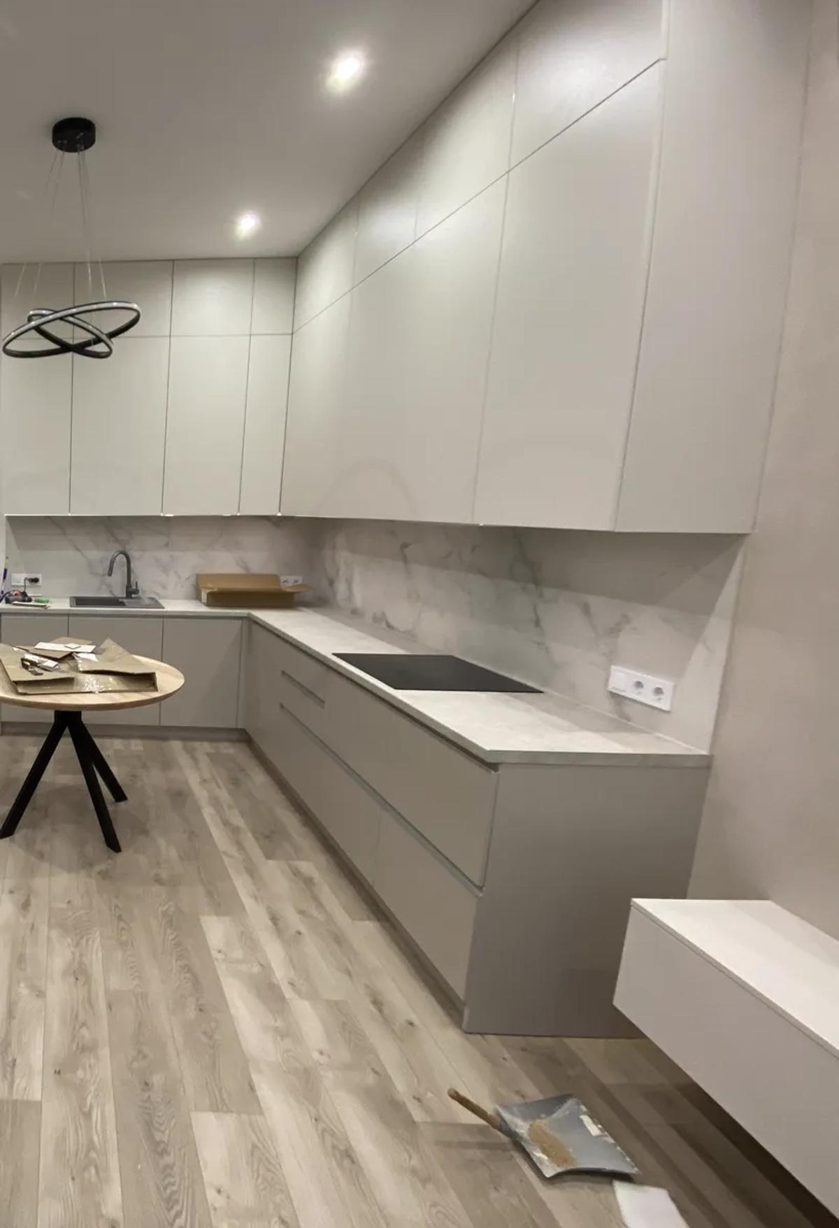 Cocina gris en L abierta al salón con frente efecto mármol tras la reforma, Valencia