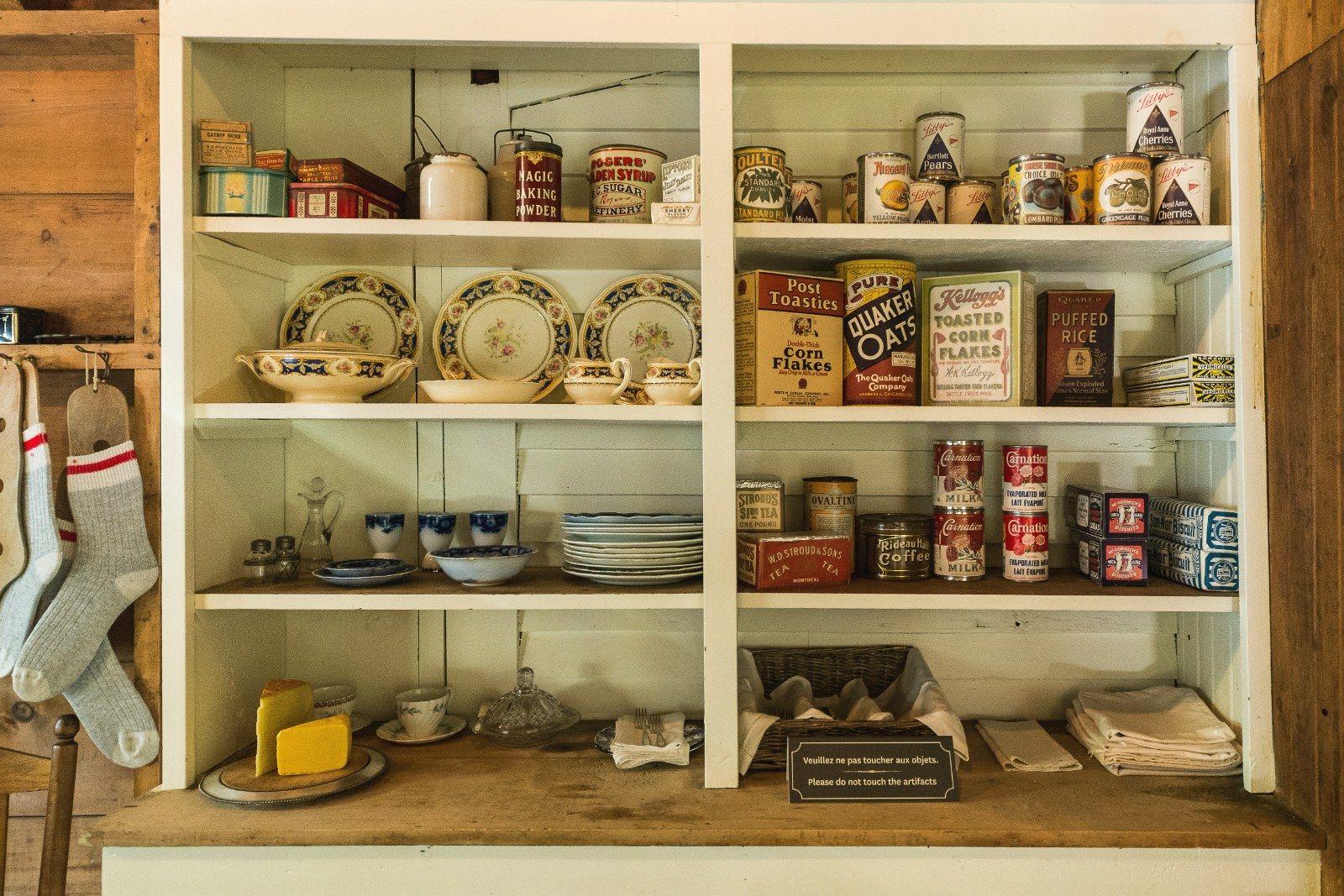 A wooden dresser with shelves of vintage packaged food tins and crockery.