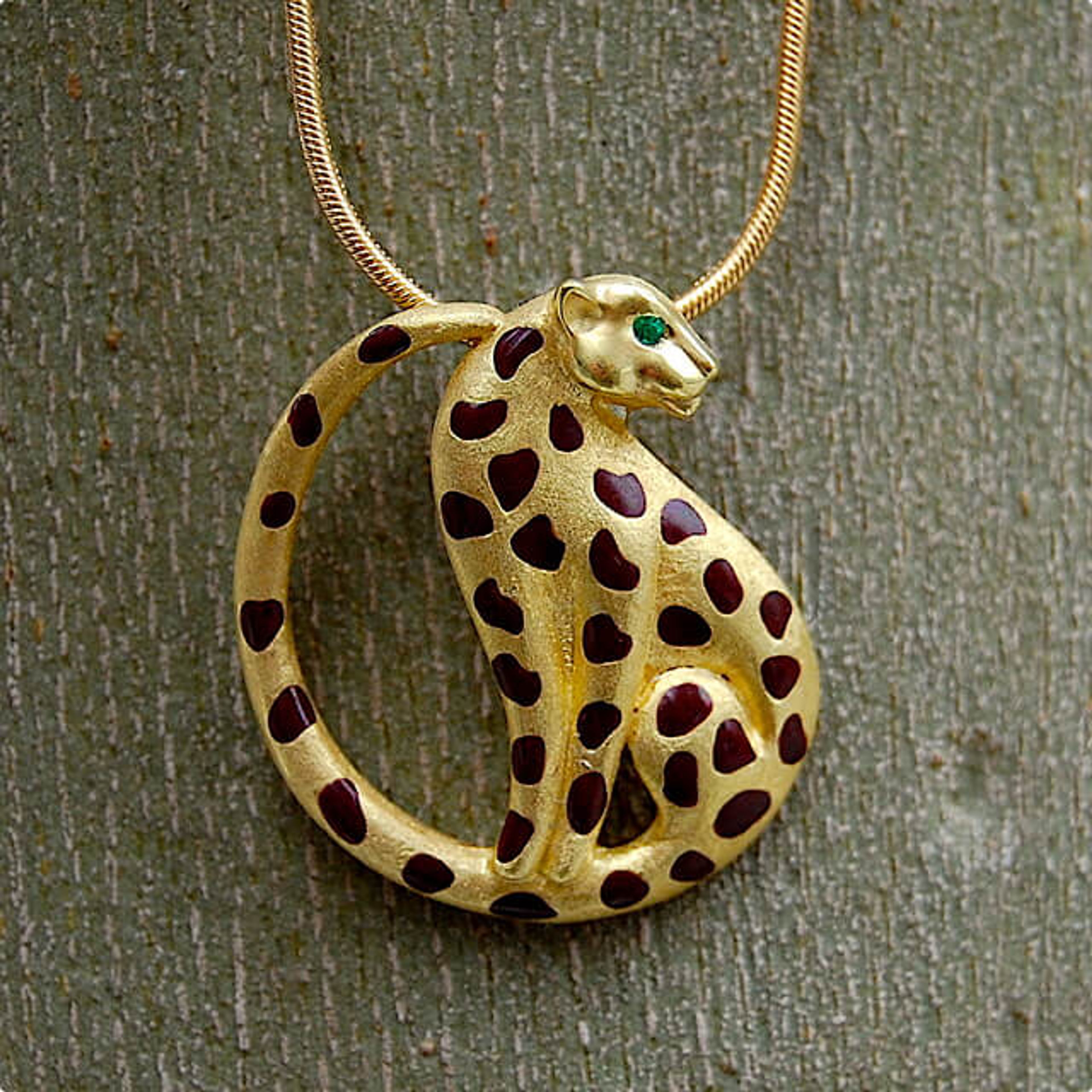 Gold pendant of a leaopard with brown spots and a green jem eye