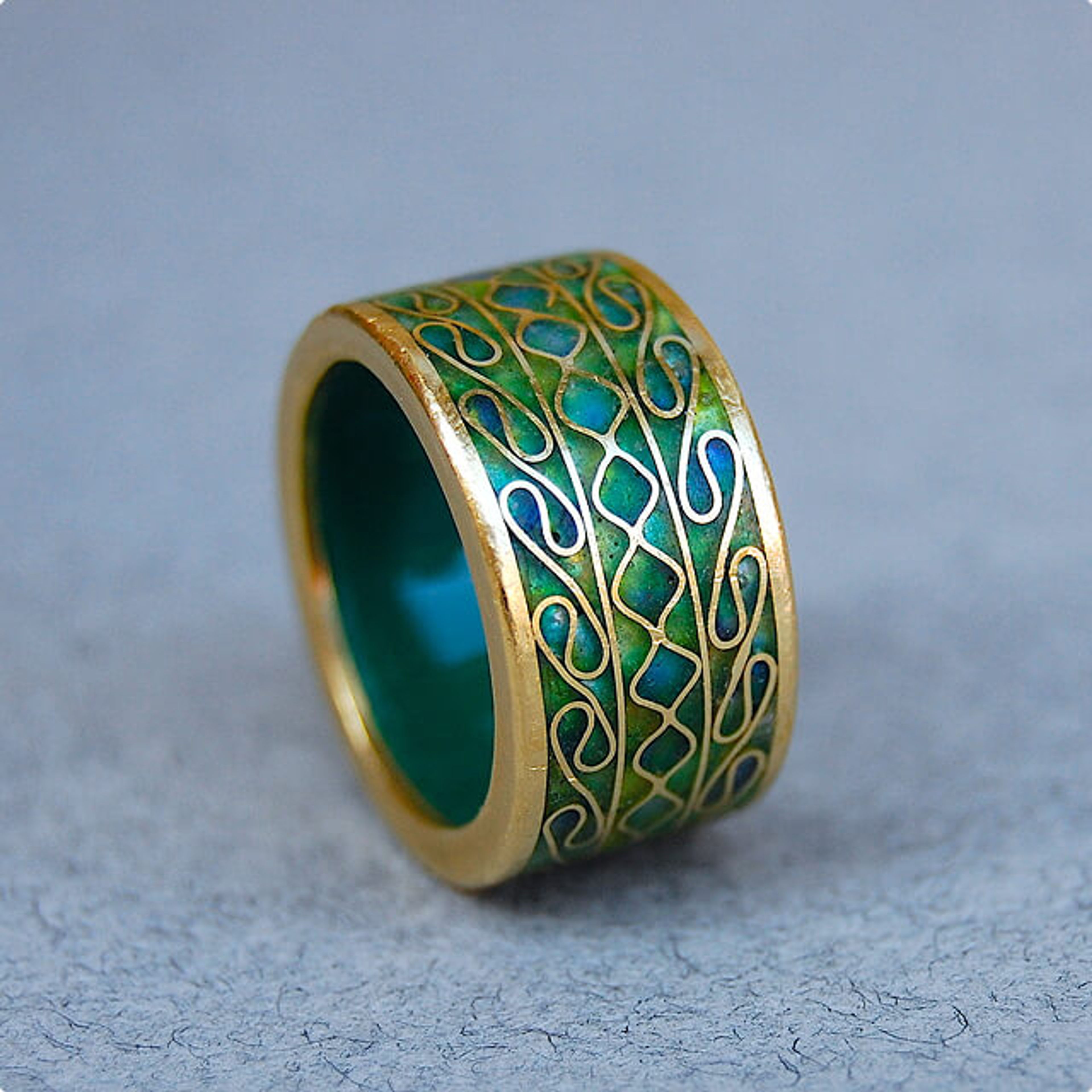 Gold ring with green and blue enamel and intricate gold patterns