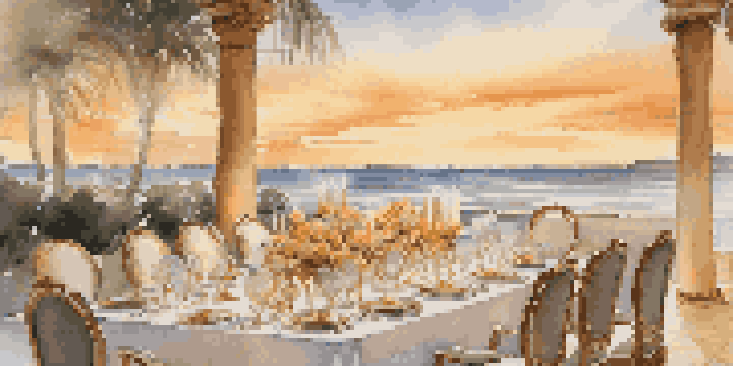 An elegant outdoor dining table at sunset, adorned with fine china and crystal glassware, overlooking a tranquil beach.