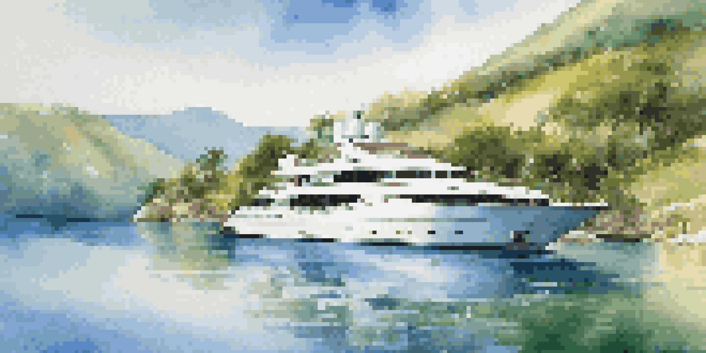An elegant yacht in a beautiful bay with sun loungers and a dining area on the deck.