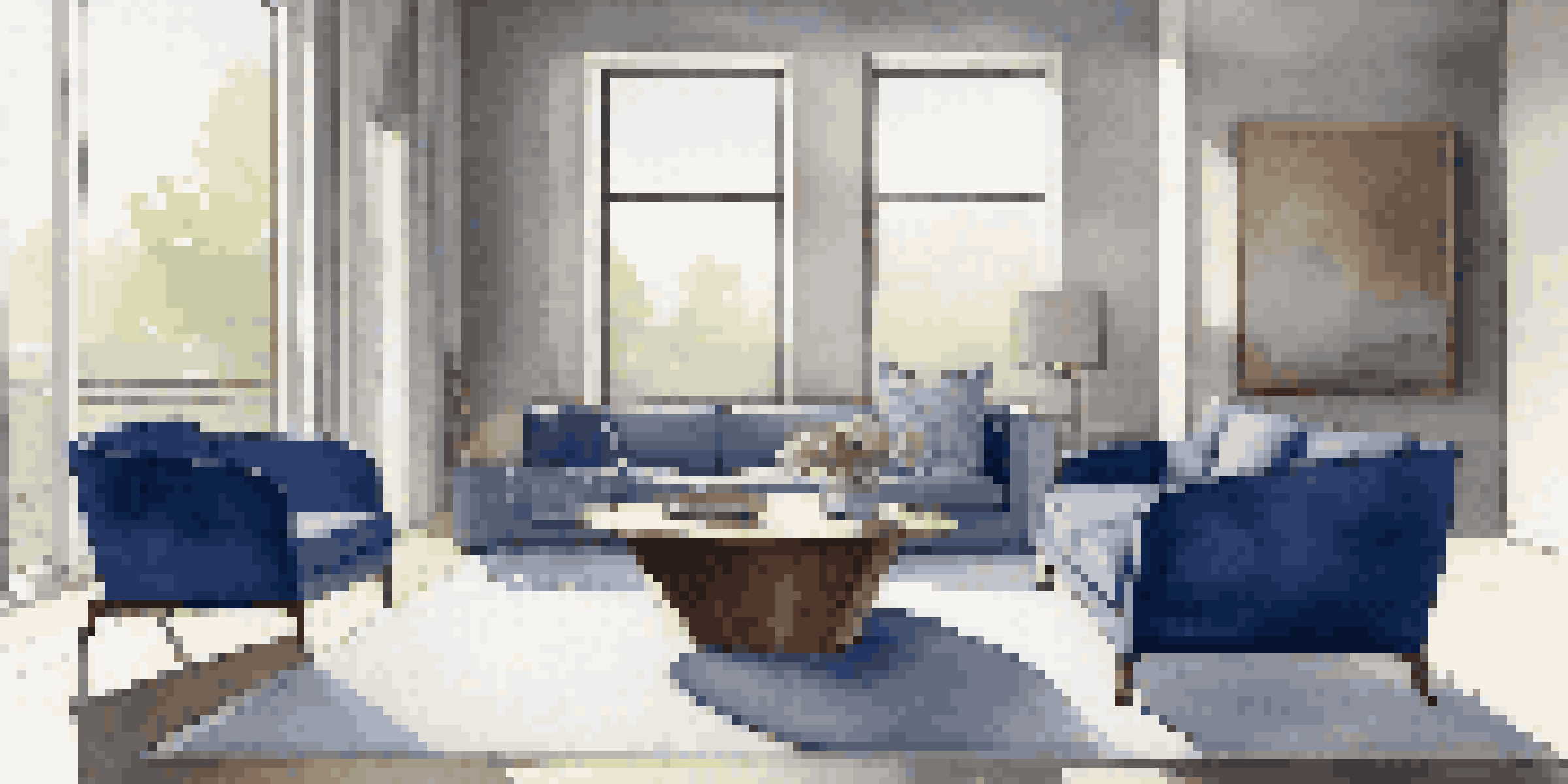 A minimalist living room with a walnut coffee table, cobalt blue chair, and soft gray walls illuminated by natural light.