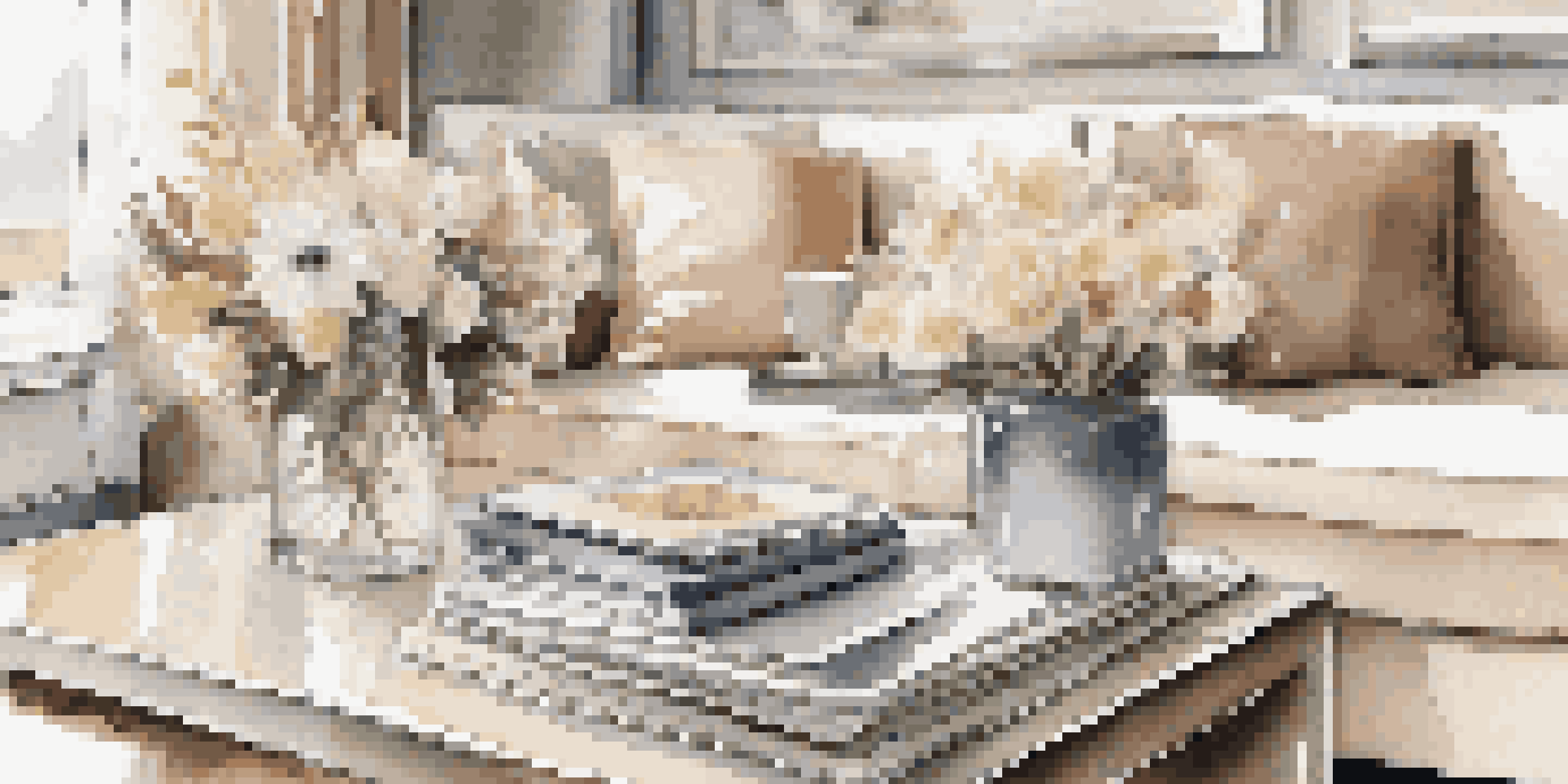 A stylish coffee table with luxury magazines, a porcelain teacup, and fresh flowers in a sunlit modern living room.