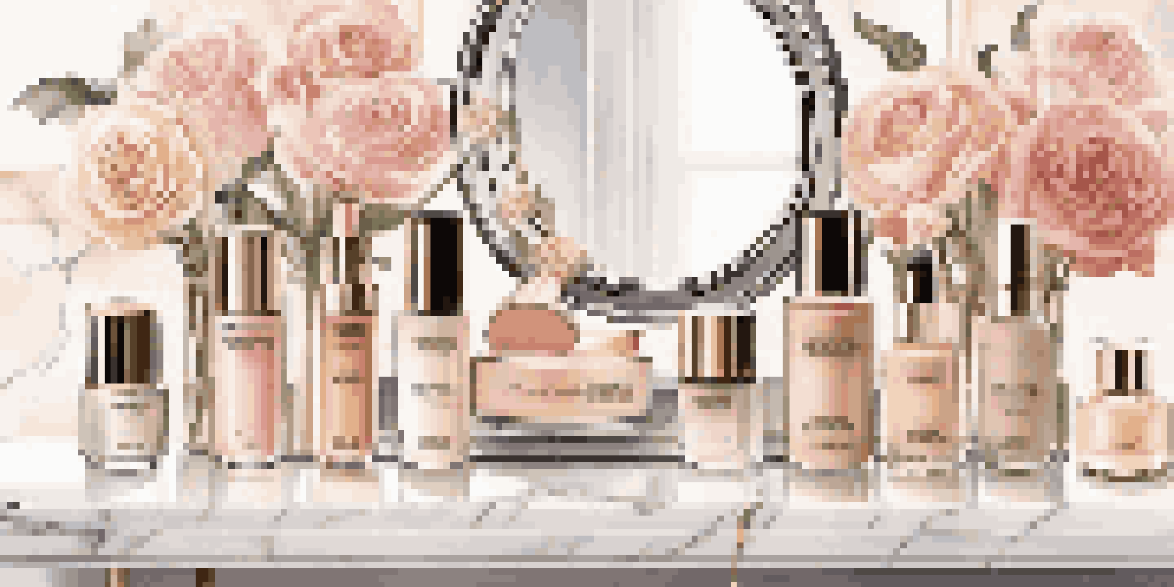 A beautifully arranged display of luxury foundation bottles on a marble vanity, surrounded by flowers and makeup brushes under soft lighting.