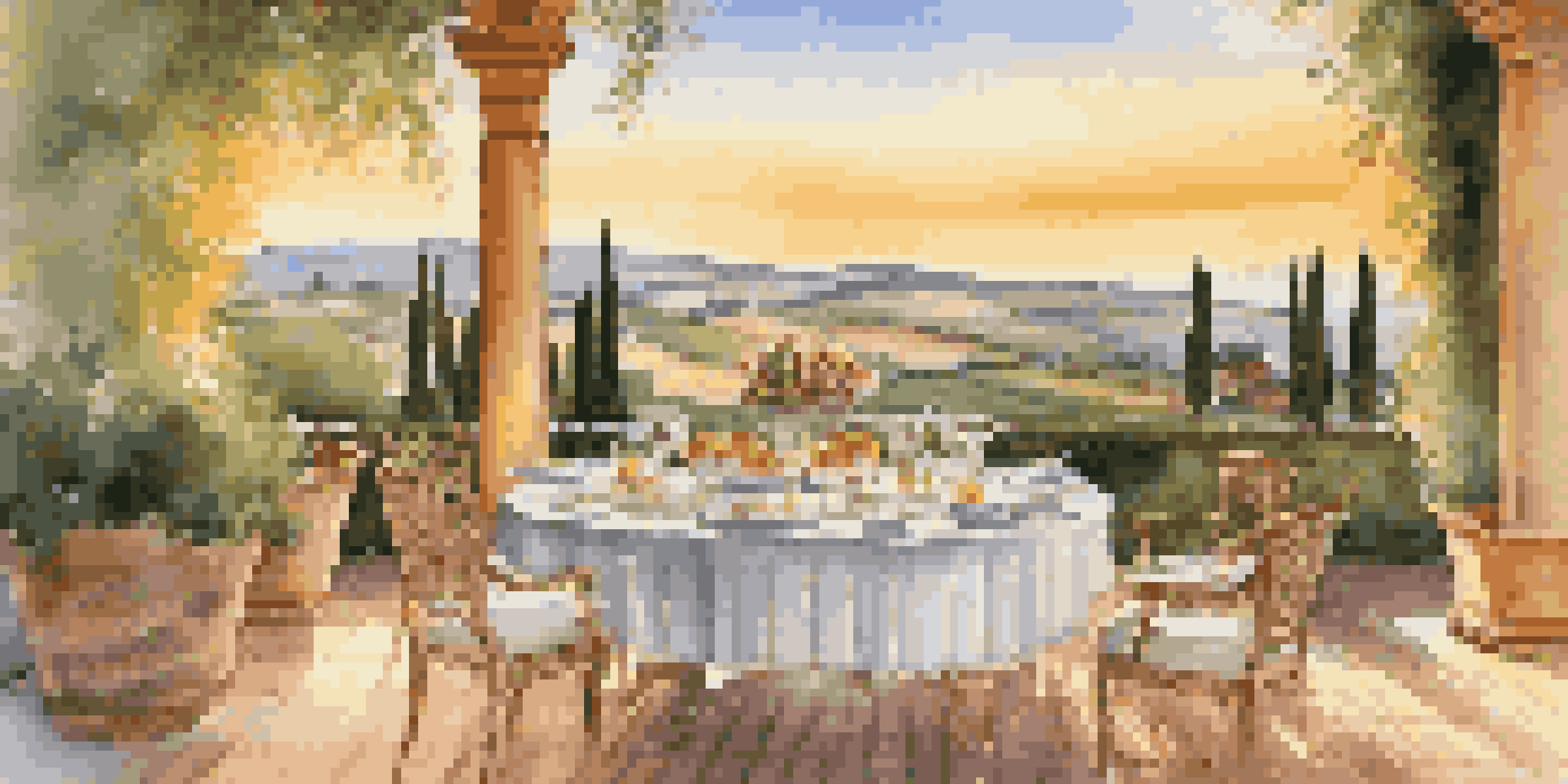 An elegant outdoor dining setup on a terrace with a beautiful view of the Tuscan countryside during sunset.